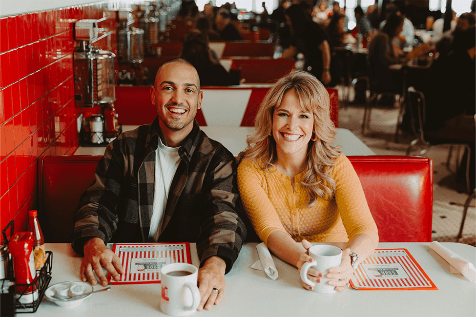 Carlos and Amy laughing and smiling together with a city scape behind them